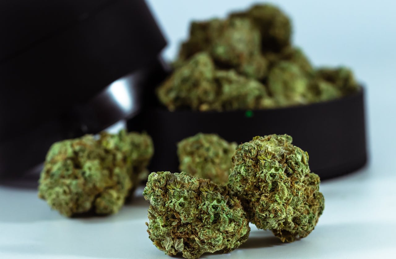 A detailed close-up of dried cannabis buds with a blurred container backdrop, perfect for medical or recreational usage content.